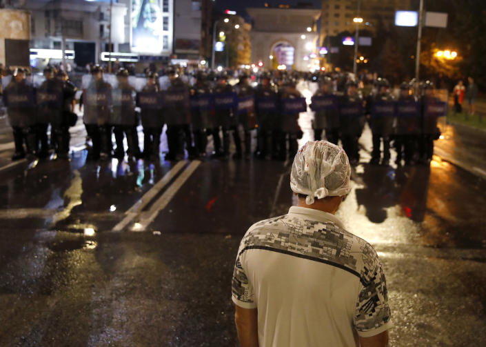 A man with a plastic bag on his head looks at police cordon during a protest at the parliament building in Skopje, North Macedonia, late Tuesday, July 5, 2022. Violent protests erupted in North Macedonia's capital, Skopje, where demonstrators tried to storm government buildings, after French President Emmanuel Macron last week announced the proposal, which many in the small Balkan country find controversial. (AP Photo/Boris Grdanoski)