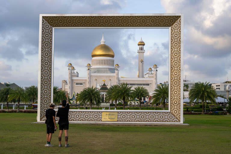 Turistas fotografían la mezquita del sultán Omar Ali Saifuddien, en Bandar Seri Begawan, el 11 de enero de 2024.  (Mohd RASFAN / AFP)