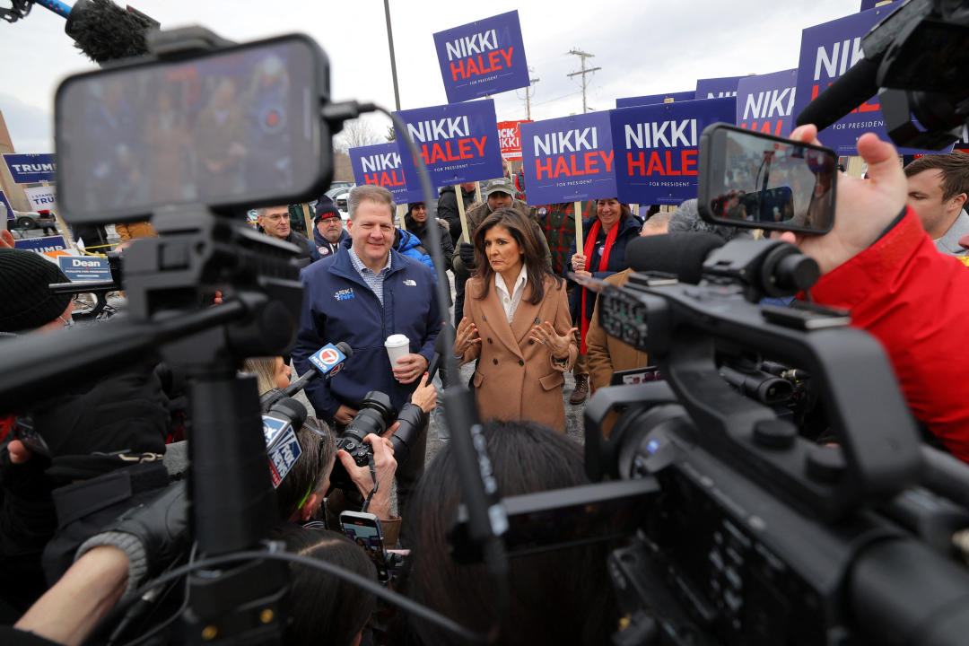 Nikki Haley and Chris Sununu stand among reporters and people holding signs that read: Nikki Haley.