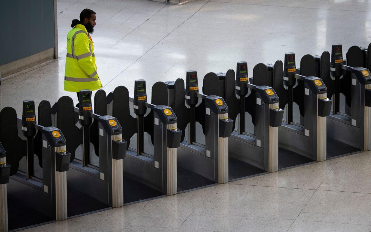 Train station staff member waits next to empty ticket gates at Waterloo Station in London during industrial strike action by rail workers and train drivers - TOLGA AKMEN/EPA-EFE/Shutterstock