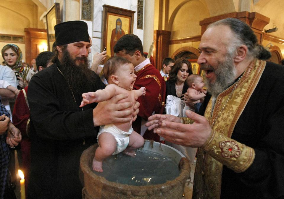 Georgian babies are baptized at the Holy Trinity Cathedral in Tbilisi, Georgia, on Sunday, May 6, 2012. Many of the parents of the 400 babies baptized on Sunday said Georgian Orthodox Church Patriarch Ilia II was instrumental in their decision to have a third or fourth child. Patriarch Ilia II promised to become the godfather of all babies born into Orthodox Christian families who already have two or more children and since 2008 has gained nearly 11,000 godchildren. (AP Photo/ Shakh Aivazov)