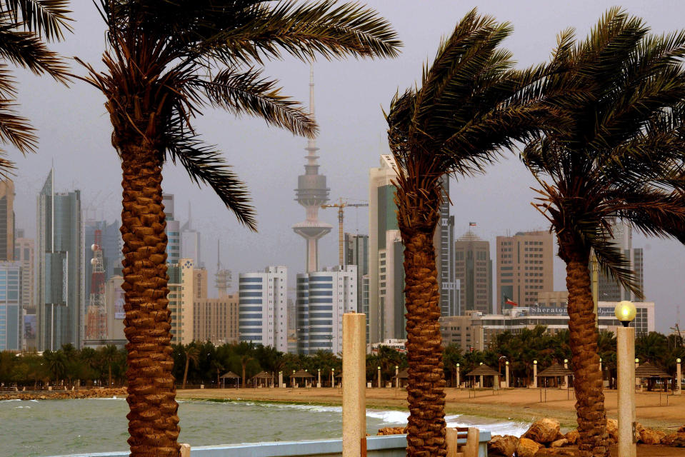 FILE- In this April 16, 2009 file photo, the Kuwait city skyline is seen through the haze of a sand storm in Kuwait City. Kuwait, one of the world’s wealthiest countries, is facing a debt crisis. The pandemic has sent the price of oil crashing to all-time lows and pushed Kuwait toward a reckoning with its longtime largesse for its citizens just as a parliamentary election looms in Dec. 2020. It needs the new parliament to approve raising its debt spending and passing the bill will be the first legislative challenge for Kuwait's new emir. (AP Photo, File)