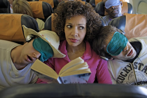 Woman sat on plane two men asleep on her shoulders