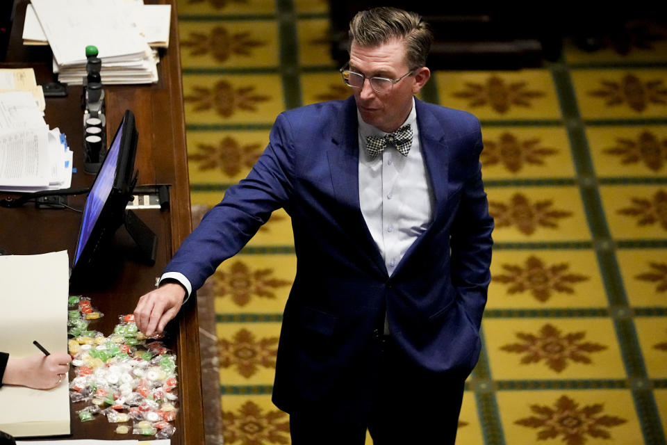 Rep. Ryan Williams, R-Cookeville, reaches for a piece of candy on the clerk's desk in the House chamber during a legislative session Tuesday, April 23, 2024, in Nashville, Tenn. State Republican lawmakers have passed a bill, sponsored by Williams, that would let some teachers and staff carry concealed handguns on public school grounds. (AP Photo/George Walker IV)