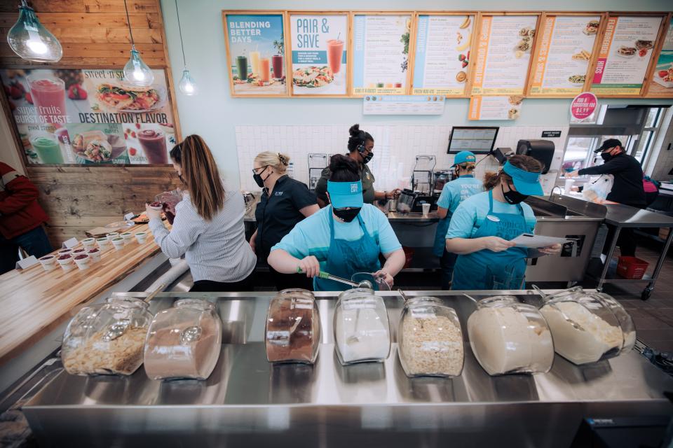 Workers prepare drinks and food for the ever-increasing flow of customers during the grand opening of Tropical Smoothie Cafe in January 2022.