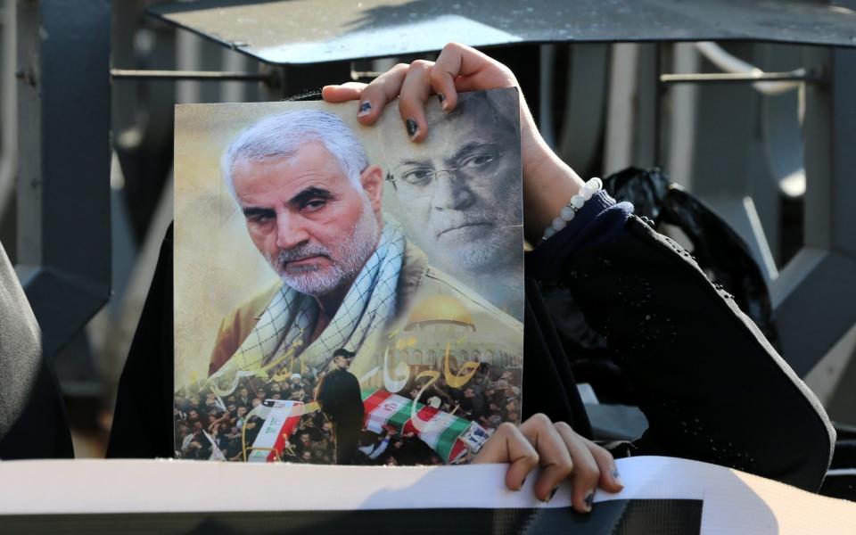 An Iraqi woman holds a picture of Qassim Soleimani and Iraqi militia commander Abu Mahdi al-Muhandis during a demonstration on the first anniversary of a US drone attack that killed the two men.  - Shutterstock