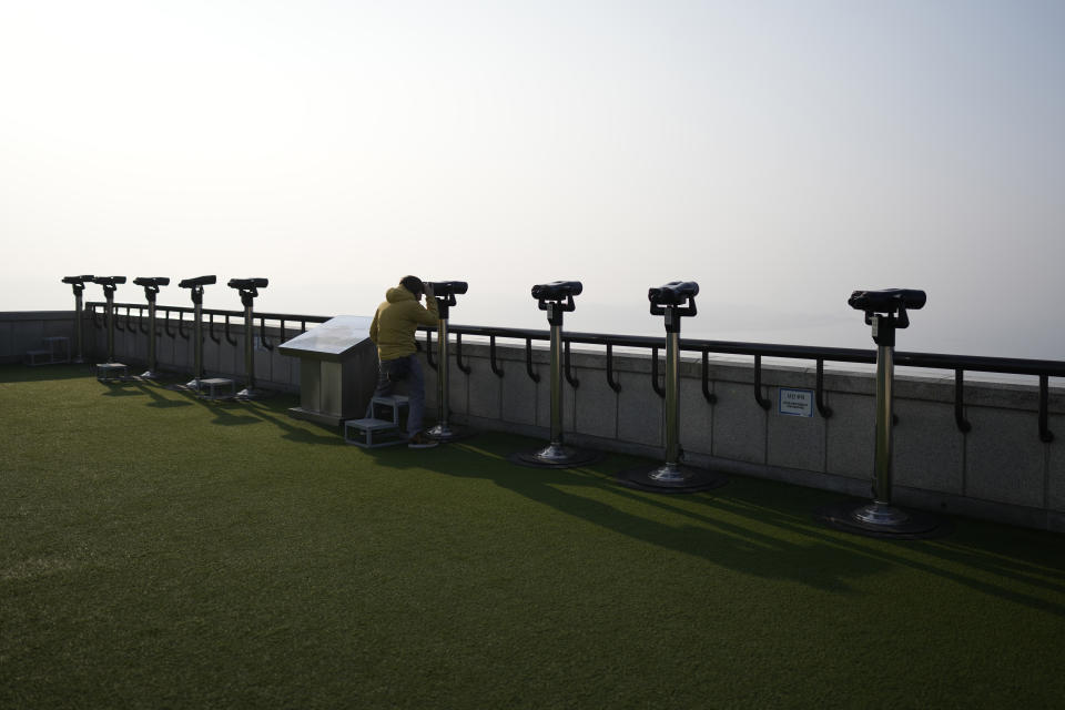 A visitor uses a pair of binoculars to see the North Korean side from the unification observatory, in Paju, South Korea, Friday, Jan. 5, 2024. North Korea fired artillery rounds Friday near its disputed sea boundary with South Korea in violation of a fragile 2018 military agreement, officials said, prompting the South to plan similar drills. (AP Photo/Lee Jin-man)