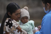 Marina, who did not want to give her last name, is given vitamins for her child from a Health Ministry worker who is going house to house in the Cotopaxi province of Ecuador, Friday, Dec. 2, 2022. Child malnutrition is chronic among Ecuador's 18 million inhabitants, hitting hardest in rural areas and among the country's Indigenous, according to Erwin Ronquillo, secretary of the government program Ecuador Grows Without Malnutrition. (AP Photo/Dolores Ochoa)