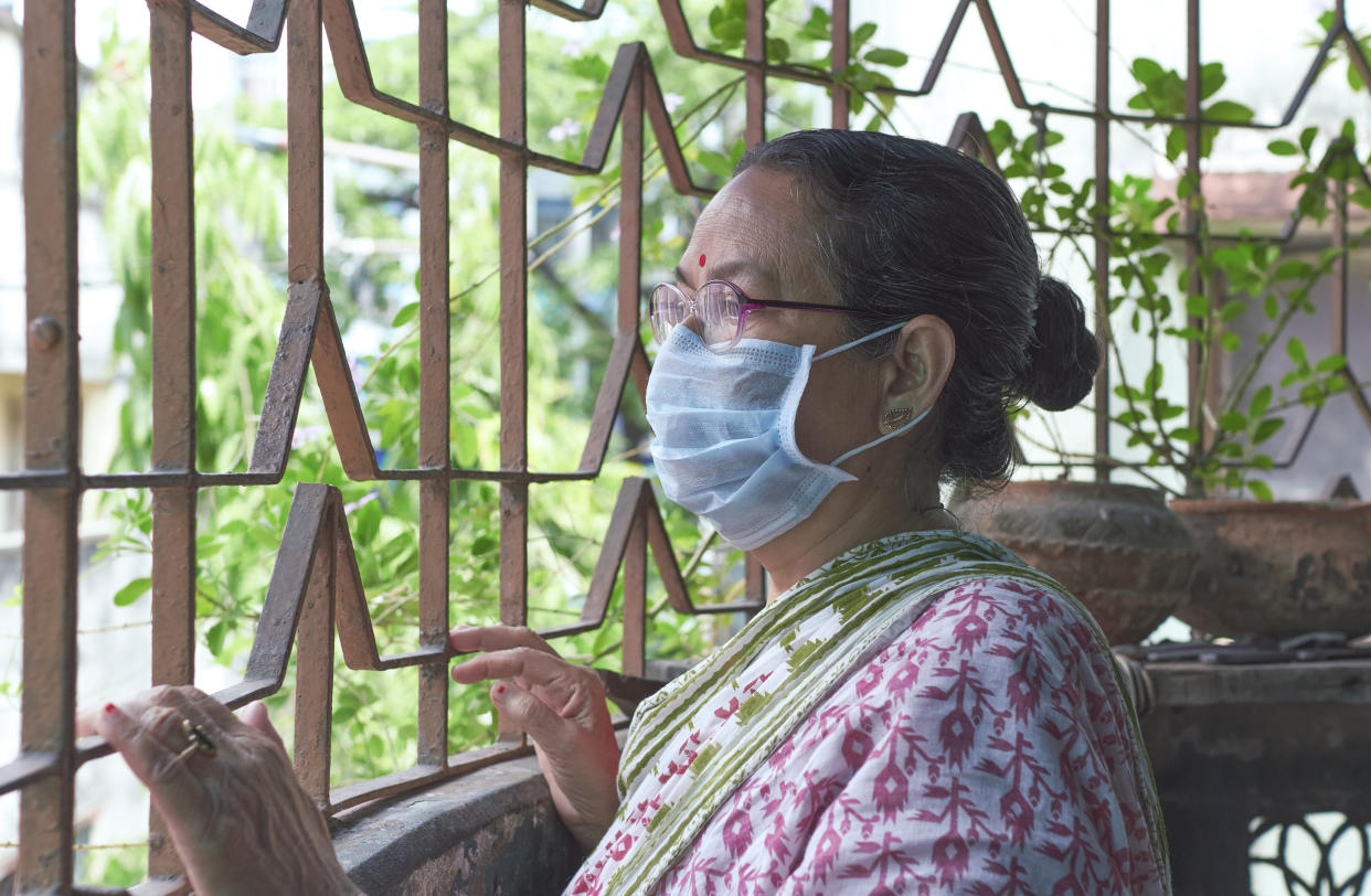 An aged Indian woman looking out of verandah in her house, wearing face mask during coronavirus lockdown in Kolkata. Concept of home isolation in fight against coronavirus.
Photo taken in Kolkata on 04/26/2020.