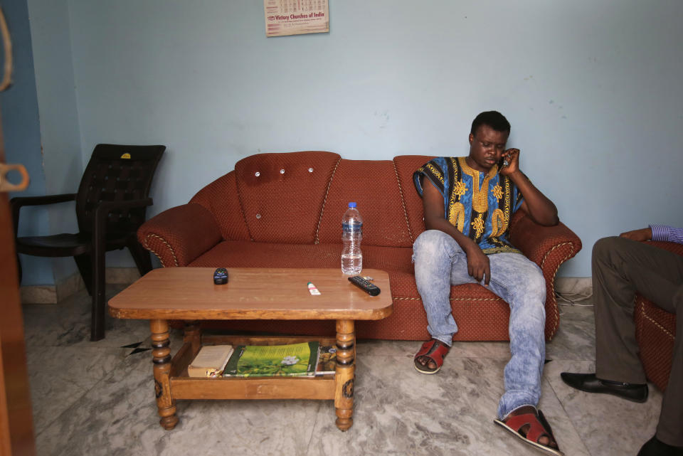 In this Friday, March 31, 2017 photo, Nigerian student Precious Amalawa, who along with his brother Endurance had come to seek better education and work opportunities in India, speaks on his mobile phone to his parents inside his apartment in Greater Noida, India. Both were victims of violence that started March 24 when a teenage boy disappeared in Greater Noida, outside New Delhi, and angry relatives claimed he'd been killed by his Nigerian neighbors. A mob of people began searching the area for Africans, with some accusing kidnappers of eating the boy. (AP Photo/Altaf Qadri)