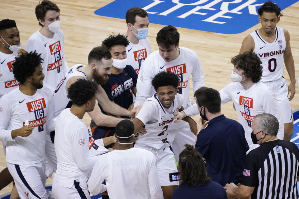 Virginia guard Reece Beekman (2) is swarmed by teammates after sinking the winning shot during the second half of an NCAA college basketball game against Syracuse in the quarterfinal round of the Atlantic Coast Conference tournament in Greensboro, N.C., Thursday, March 11, 2021. Virginia Won the game 72-69. (AP Photo/Gerry Broome)