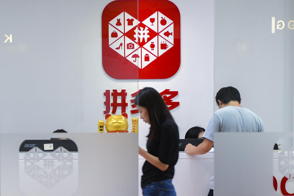 A woman walks past the reception desk at the headquarters of Pinduoduo with the logo displayed in the background in Shanghai, on July 25, 2018. Google on Tuesday, March 21, 2023 has suspended the Chinese shopping app Pinduoduo on its app store after malware was discovered in versions of the app from other sources. (Chinatopix via AP)