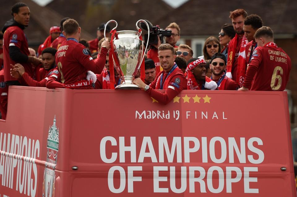 Liverpool's English midfielder Jordan Henderson (C) holds the European Champion Clubs' Cup trophy during an open-top bus parade around Liverpool, north-west England on June 2, 2019, after winning the UEFA Champions League final football match between Liverpool and Tottenham. - Liverpool's celebrations stretched long into the night after they became six-time European champions with goals from Mohamed Salah and Divock Origi to beat Tottenham -- and the party was set to move to England on Sunday where tens of thousands of fans awaited the team's return. The 2-0 win in the sweltering Metropolitano Stadium delivered a first trophy in seven years for Liverpool, and -- finally -- a first win in seven finals for coach Jurgen Klopp. (Photo by Oli SCARFF / AFP)        (Photo credit should read OLI SCARFF/AFP/Getty Images)