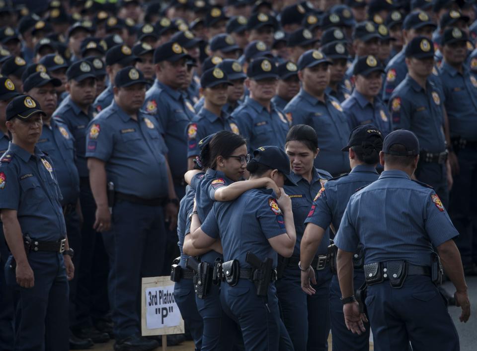 A policewoman (C) is helped by colleagues during an inspection and accounting of personnel by the regional police chief at the police district of Manila, the Philippines. (Photo: TED ALJIBE/AFP/Getty Images)
