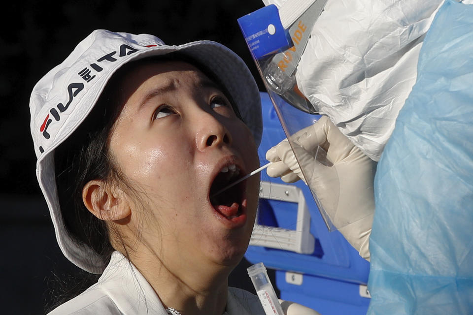 A medical staff conducts a nucleic acid test on a foreign reporter who was selected to cover the closing session of the Chinese People's Political Consultative Conference (CPPCC) for the coronavirus test, at a hotel in Beijing, Wednesday, May 27, 2020. (AP Photo/Andy Wong)