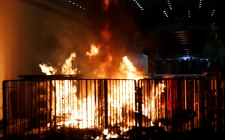 A barricade burns as riot police stand guard, after a march to call for democratic reforms in Hong Kong