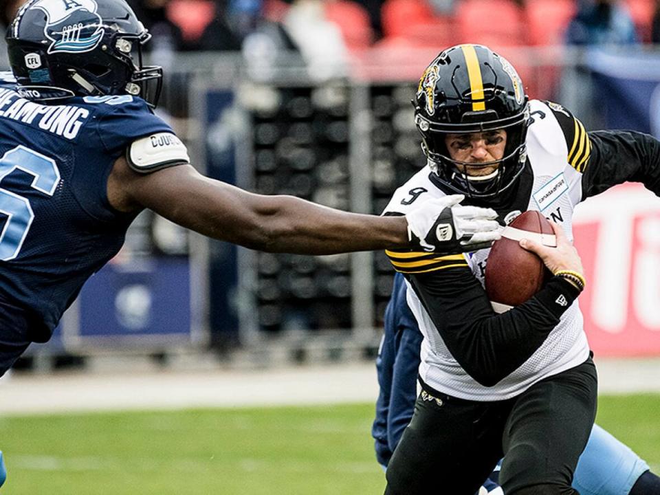 Tiger-Cats quarterback Dane Evans evades Argonauts defensive lineman Sam Acheampong during first-half play in the CFL East final on Sunday in Toronto. (Christopher Katsarov/Canadian Press - image credit)