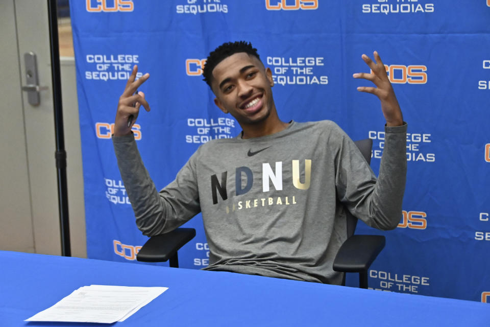 In this Jan. 31, 2020, photo provided by Tim Foster, Savion Johnson reacts after he signed his acceptance letter to Notre Dame de Namur University during a ceremony at the College of the Sequoias gym in Visalia, Calif. Johnson was set to transfer this fall from a junior college in California to Notre Dame de Namur University in the San Francisco Bay Area as a Division 2 basketball recruit. As the coronavirus spread, Johnson received a text from the basketball coach rescinding his offer. The school, immersed in deep financial problems amid dwindling enrollment, decided to cancel the incoming freshman class and competitive sports as it tries to avert total closure. (Tim Foster via AP)