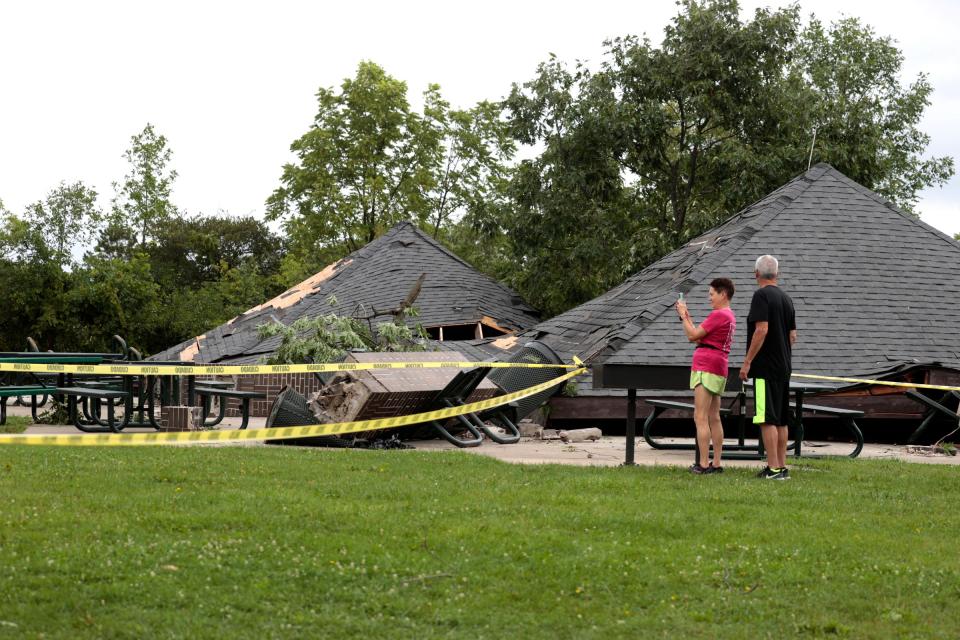 A couple look over and take pictures of the damaged pavilions and park area at Heritage Park in Canton on Friday, August 25, 2023.
High winds and rain caused the damage late Thursday night and early Friday morning.