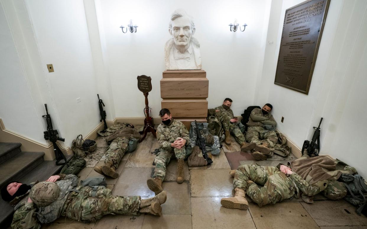 Members of the National Guard try to get some sleep inside the US Capitol in Washington - Shutterstock