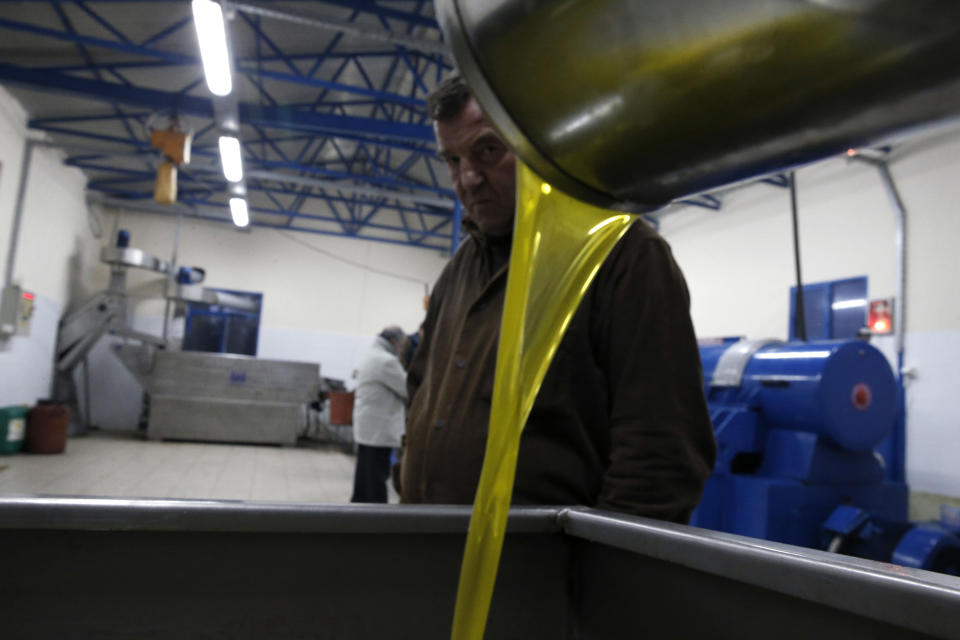 A customer watches olive oil pouring out of a processing machine at a family-owned plant in Velanidi village, 320 kilometers (200 miles) west of Athens, Greece, on Thursday, Nov. 28, 2013. Greece remains the highest consumer of olive oil per capita in the world despite the country's ongoing financial crisis. (AP Photo/Petros Giannakouris)