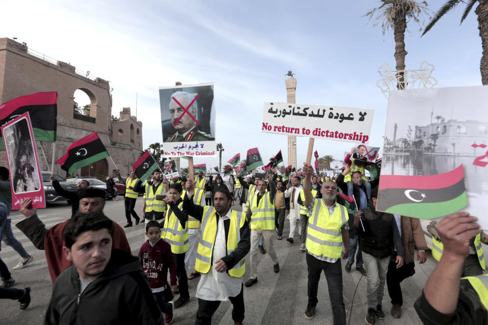 Protesters wear yellow vests at a protest in Tripoli, Libya as they wave national flags and chant slogans against Libya's Field Marshal Khalifa Hifter, who is leading an offensive to take over the capital of Tripoli, Friday, April 19, 2019. (AP Photo/Hazem Ahmed)