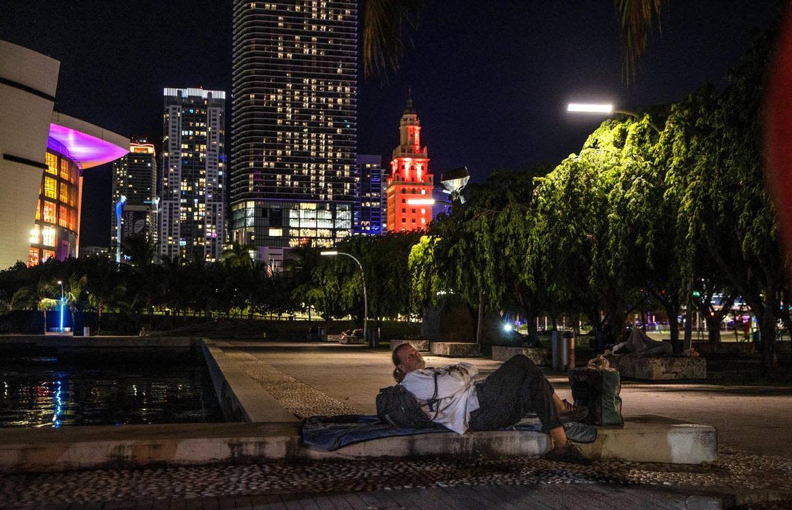A homeless man lays down on the sidewalk at Museum Park in downtown Miami, during Miami-Dade County’s annual Point-in-Time (PIT) Homeless summer census, on Thursday, Aug. 18, 2022.