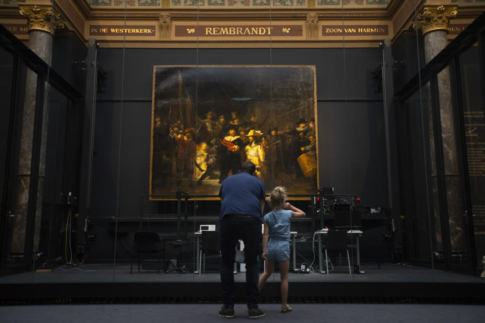 A limited amount of visitors admire Rembrandt's Night Watch, rear, at the reopened Rijksmuseum in Amsterdam, Netherlands, Monday, June 1, 2020. The Dutch government took a major step to relax the coronavirus lockdown, with bars, restaurants, cinemas and museums reopening under strict conditions. (AP Photo/Peter Dejong)