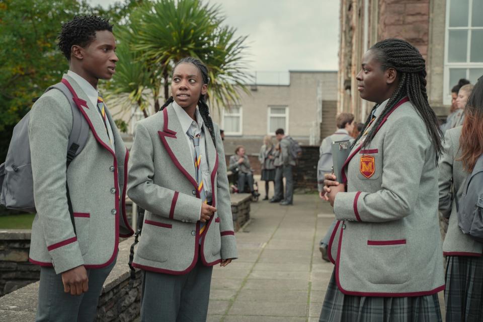 students in long grey blazers with red liner