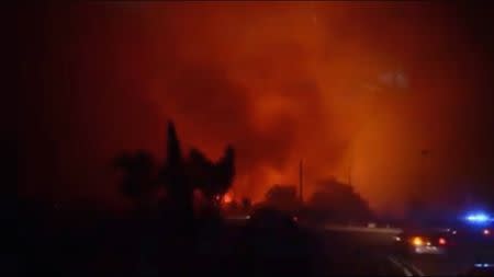 Cars drive past forest fires in Biguglia, near the town of Bastia, on Corsica island, France, July 24, 2017 in this still image from a video obtained from social media. Facebook/Florianne Amblard via REUTERS