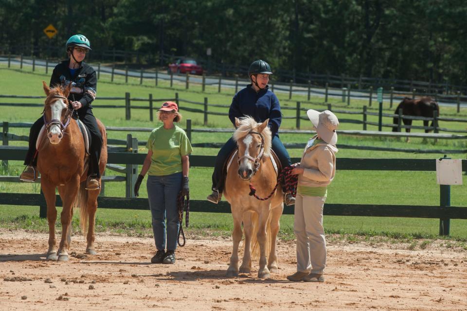 Bucky Johnson rides Charlie, and Angela rides Dixie a Haflinger pony at Prancing Horse Inc. Center for Therapeutic Riding with help from volunteers Brab Brazer, second from right, and Chris Nazario, far right in April 2015.