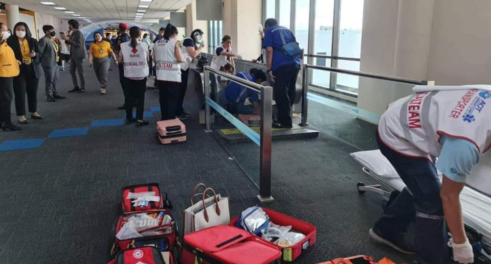 Medics tend to the woman as her leg is stuck in the travelator. 