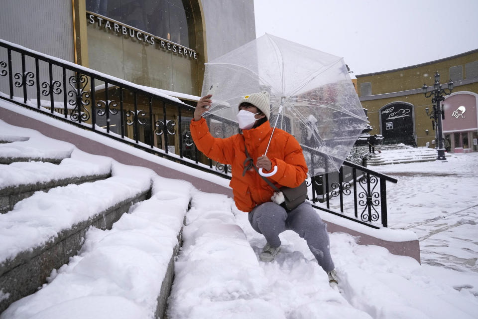 A resident takes a photo for her friend in Beijing, China, Sunday, Nov. 7, 2021. An early-season snowstorm has blanketed much of northern China including the capital Beijing, prompting road closures and flight cancellations. (AP Photo/Ng Han Guan)