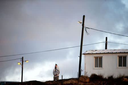 FILE PHOTO: An Israeli man wearing a Jewish prayer shawl, prays near a home in the early morning, in the Jewish settler outpost of Amona in the West Bank December 15, 2016. REUTERS/Ronen Zvulun/File Photo