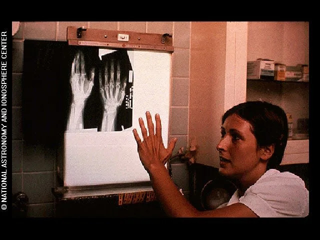 This image shows a woman looking at an x-ray photo of what seems to be her own hand. It was included in the Golden Record.