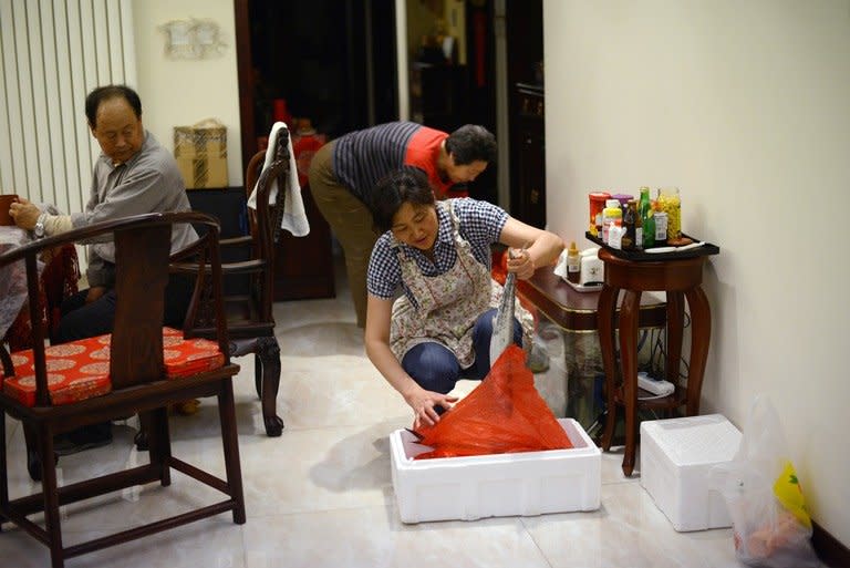 Li Na examines a fish brought from her hometown by her parents, at her home in Beijing, on May 12, 2013. With two cars, foreign holidays and a cook for their apartment, Li's family epitomises the new middle class created by China's decades of rapid economic growth