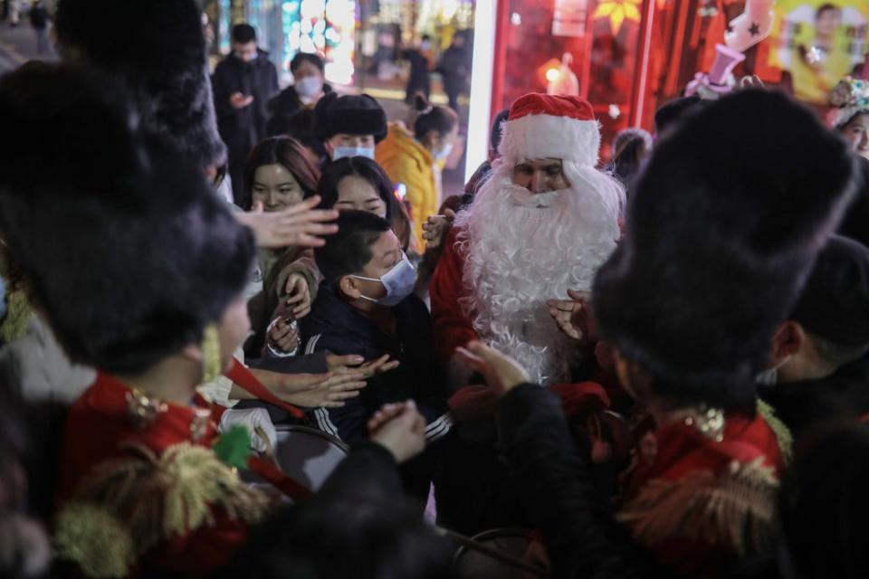 File photo: A person dressed as Santa Claus distributes gifts to people outside a shopping complex in Beijing, China, 25 December 2020 (EPA-EFE)