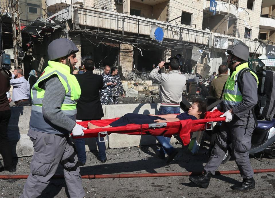 Lebanese civil defense workers carry an injured girl at the site of an explosion, near the Kuwaiti Embassy and Iran's cultural center, in the suburb of Beir Hassan, Beirut, Lebanon, Wednesday, Feb. 19, 2014. (AP Photo/Hussein Malla)