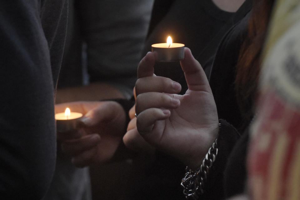 Women hold candles at the site of a deadly brawl in Koethen, 90 miles southwest of the German capital Berlin, Sunday, Sept. 9, 2018, after police has arrested two Afghan men on suspicion of killing a 22-year-old German man. (AP Photo/Jens Meyer)