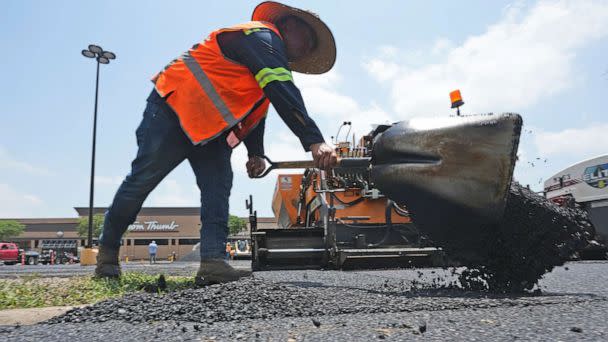 PHOTO: Miguel shovels hot asphalt during a parking lot resurfacing job in Richardson, Texas, June 20, 2023. (Lm Otero/AP)