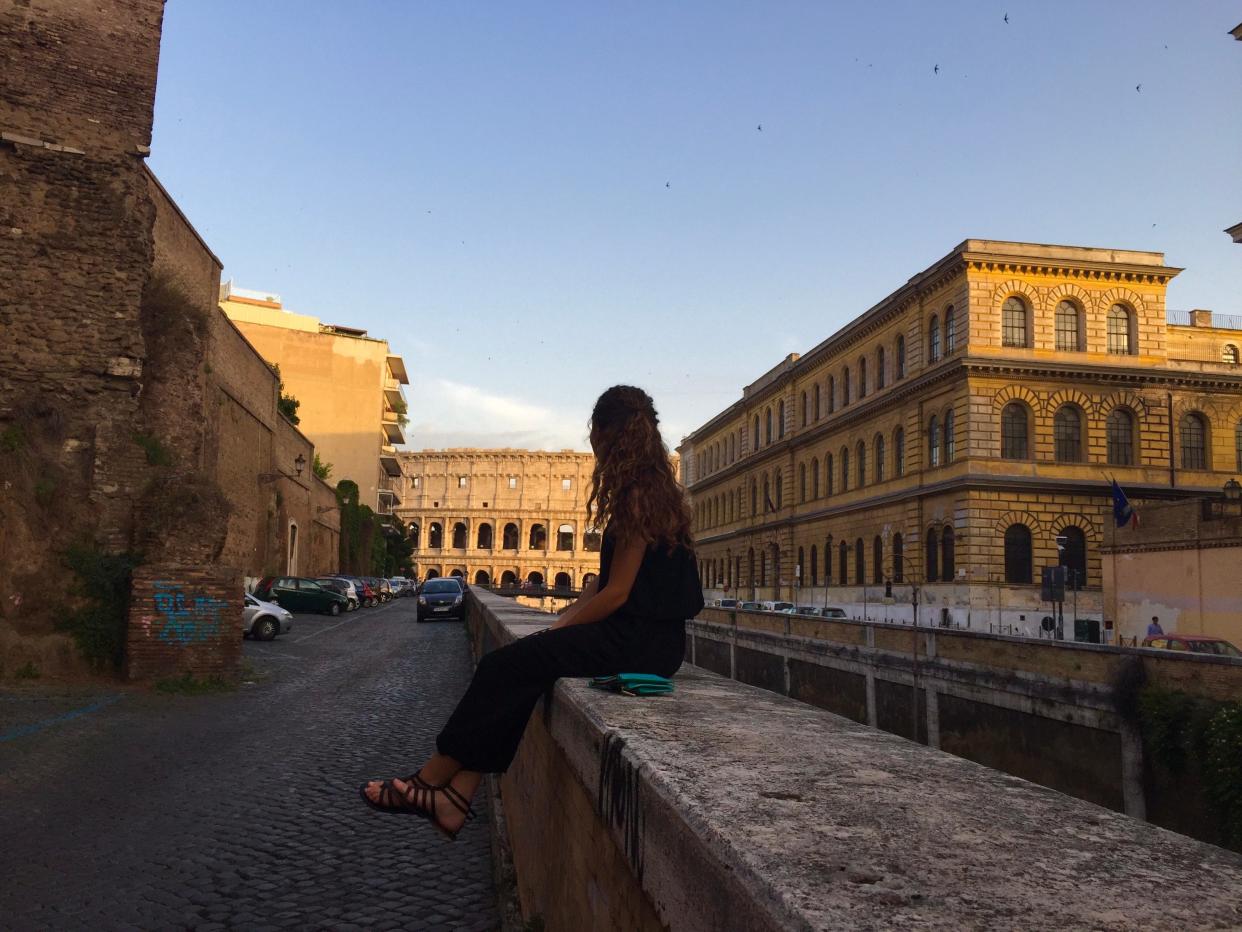 Girl sitting on a marble ledge backdropped by the Colosseum