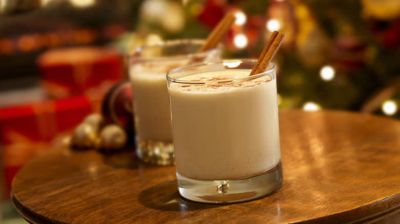 two glasses of eggnog with cinnamon sticks