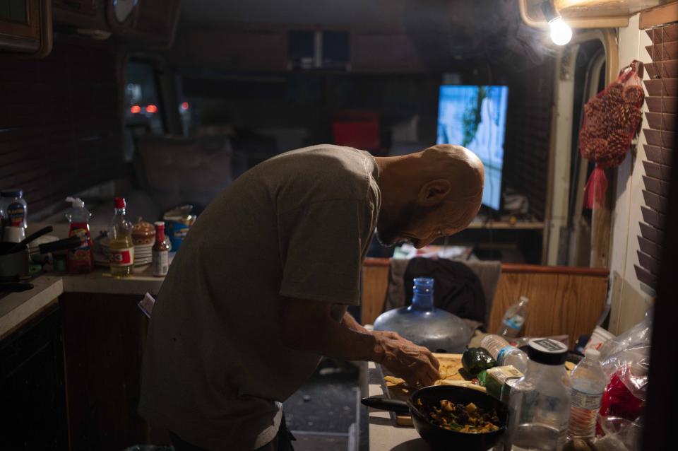 Jesse Serano, 52, prepares his dinner in an RV parked in a homeless encampment along Venice Boulevard in Los Angeles, Tuesday, Oct. 17, 2023. "We don't want money. We don't want luxury," said Serano. "We just want a decent apartment, a decent place to live and raise ourselves as humans." (AP Photo/Jae C. Hong)