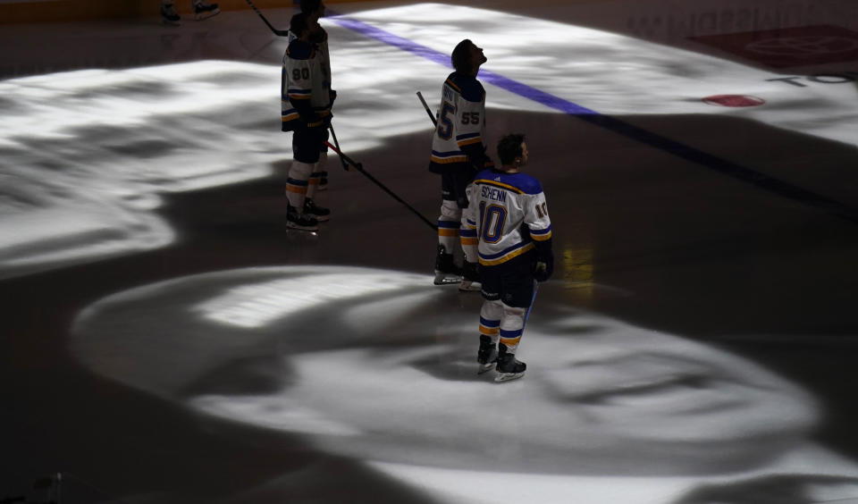 St. Louis Blues center Brayden Schenn stands on an image of former Colorado Avalanche president and general manager Pierre Lacroix projected onto the ice during a tribute Lacroix before an NHL hockey game, Wednesday, Jan. 13, 2021, in Denver. Lacroix died from complications of COVID-19 last month. (AP Photo/David Zalubowski)