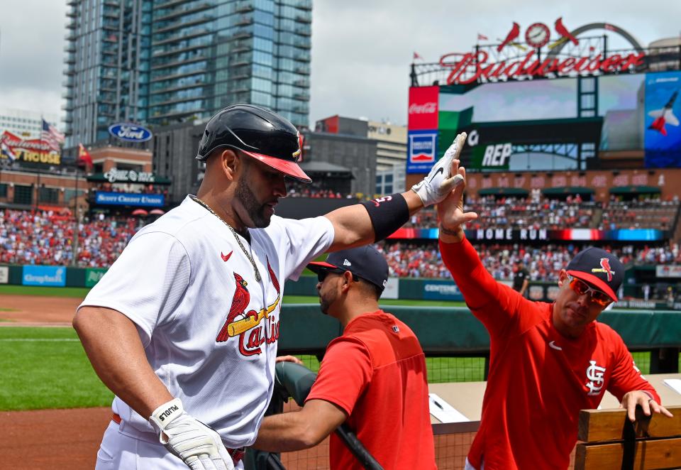 Albert Pujols of the Cardinals celebrates with bench coach Skip Schumaker after Pujols hit the first of his two home runs against the  Brewers during the second inning Sunday.