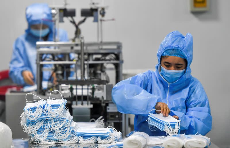 Workers make protective masks at a factory of a medical equipment maker in Urumqi, Xinjiang