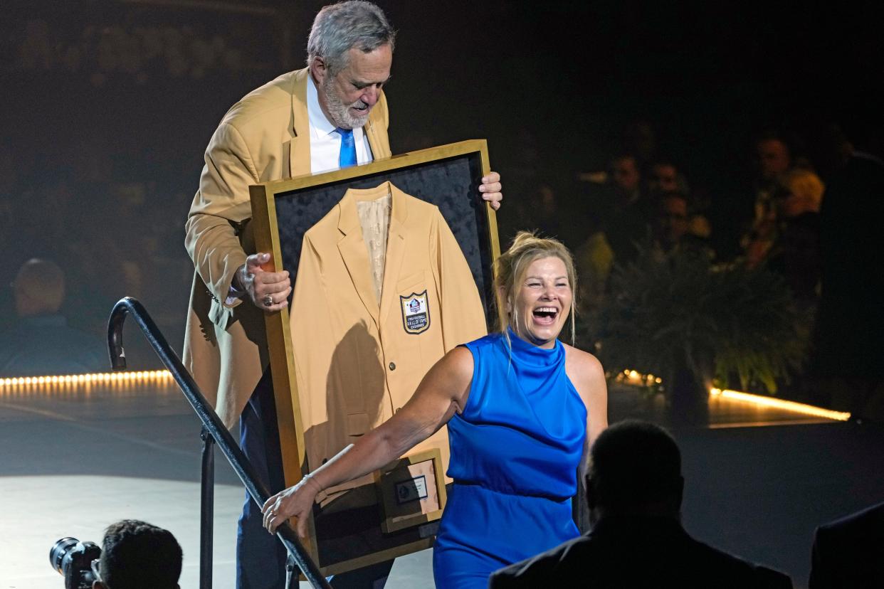 Mindy Coryell Lewis, right, daughter of Don Coryell, a member of the Pro Football Hall of Fame Class of 2023, receives her father's gold jacket with the help from Hall of Famer Dan Fouts on Friday in Canton.