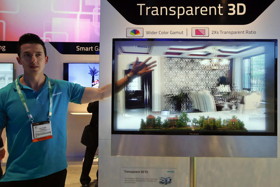 Payton Tyrell, left, demonstrates on a transparent 3D TV at the Hisense booth at the International Consumer Electronics Show.