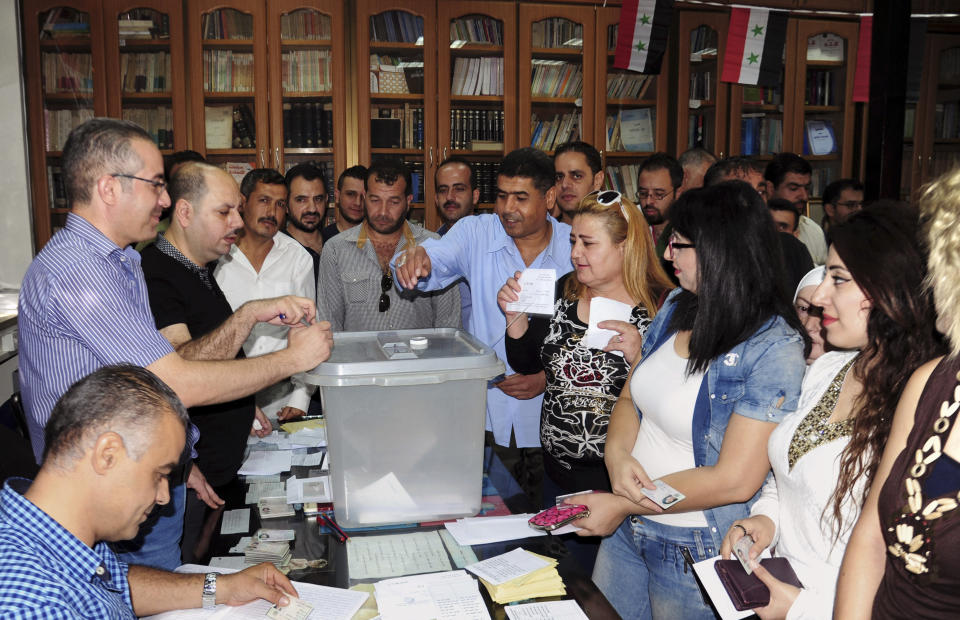 In this photo released by the Syrian official news agency SANA, Syrians cast their votes at a polling station during municipal elections, in Damascus, Syria, Sunday, Sept 16, 2018. Syria is holding its first municipal elections since 2011 amid tensions with the country's self-administered Kurdish region, which is refusing to allow polls. (SANA via AP)