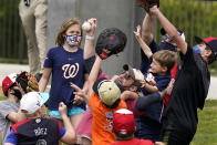 FILE - Fans wearing protective face masks go for a ball thrown from the outfield during a spring training baseball game between the Washington Nationals and New York Mets, Sunday, March 21, 2021, in West Palm Beach, Fla. Spring training games might not count in the official standings, but they certainly count for the pocketbooks of business owners in Arizona and Florida. They're also a much-anticipated destination for fans who come for the warm sunshine and the laid-back atmosphere.(AP Photo/Lynne Sladky, File)